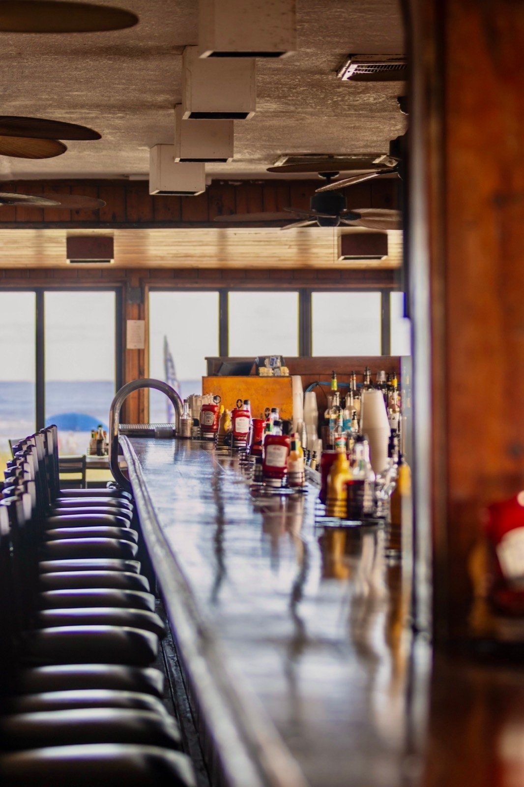 The bar at The Breakers lined with stools, looking out at the ocean through the windows