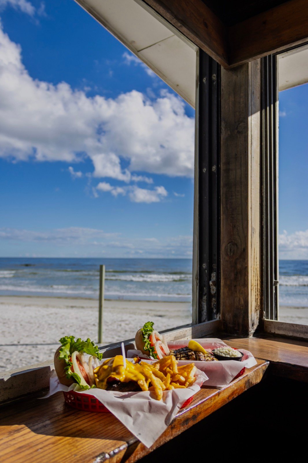 A burger and fries basket beside a grilled mahi plate