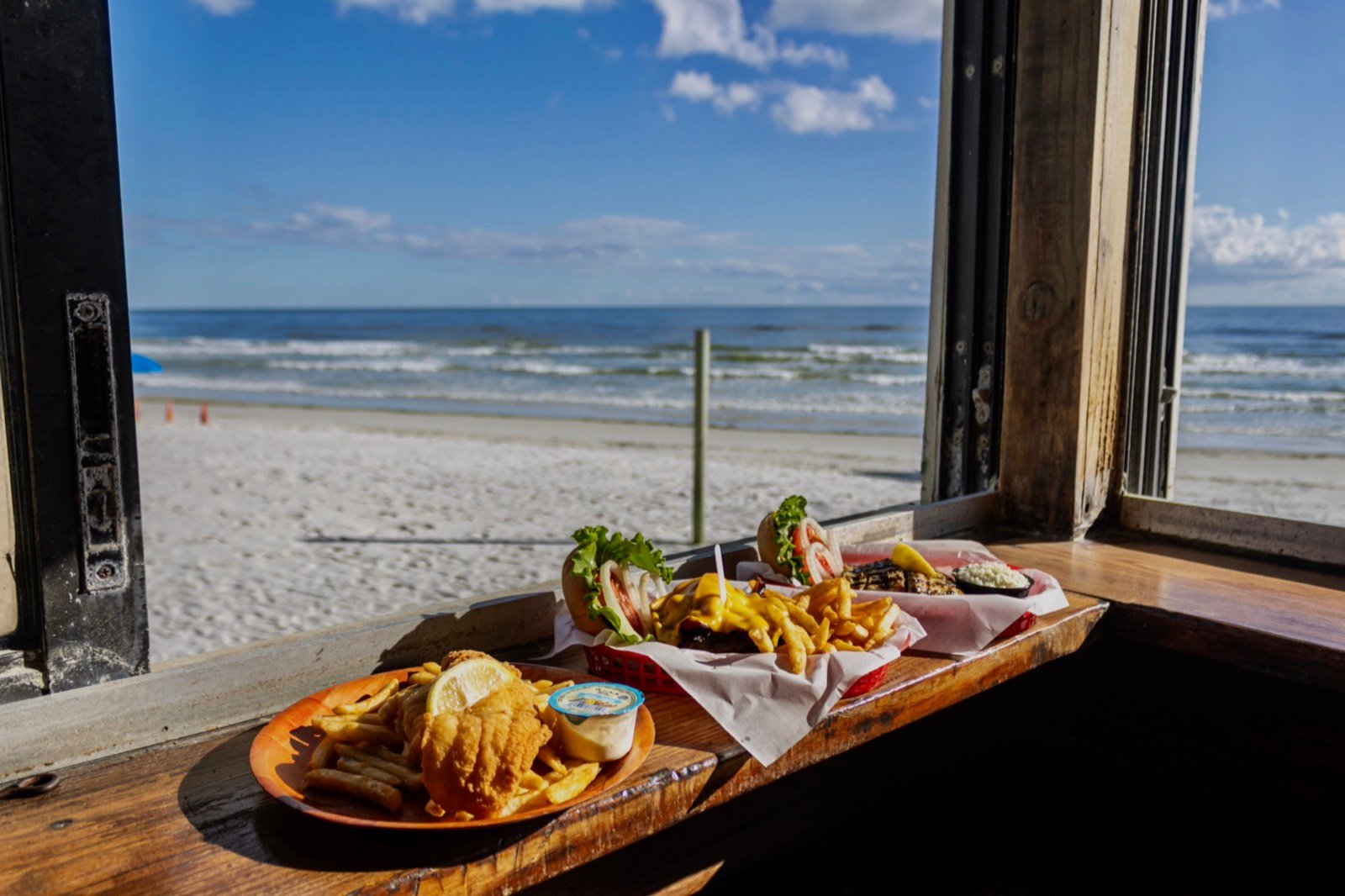 A burger plated alongside a grilled mahi sandwich