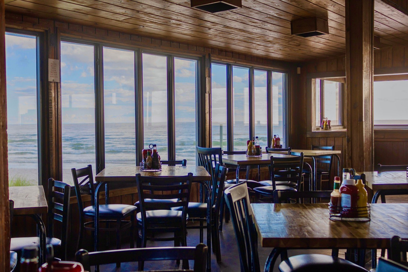 Dining tables beside floor-to-ceiling windows with an ocean view