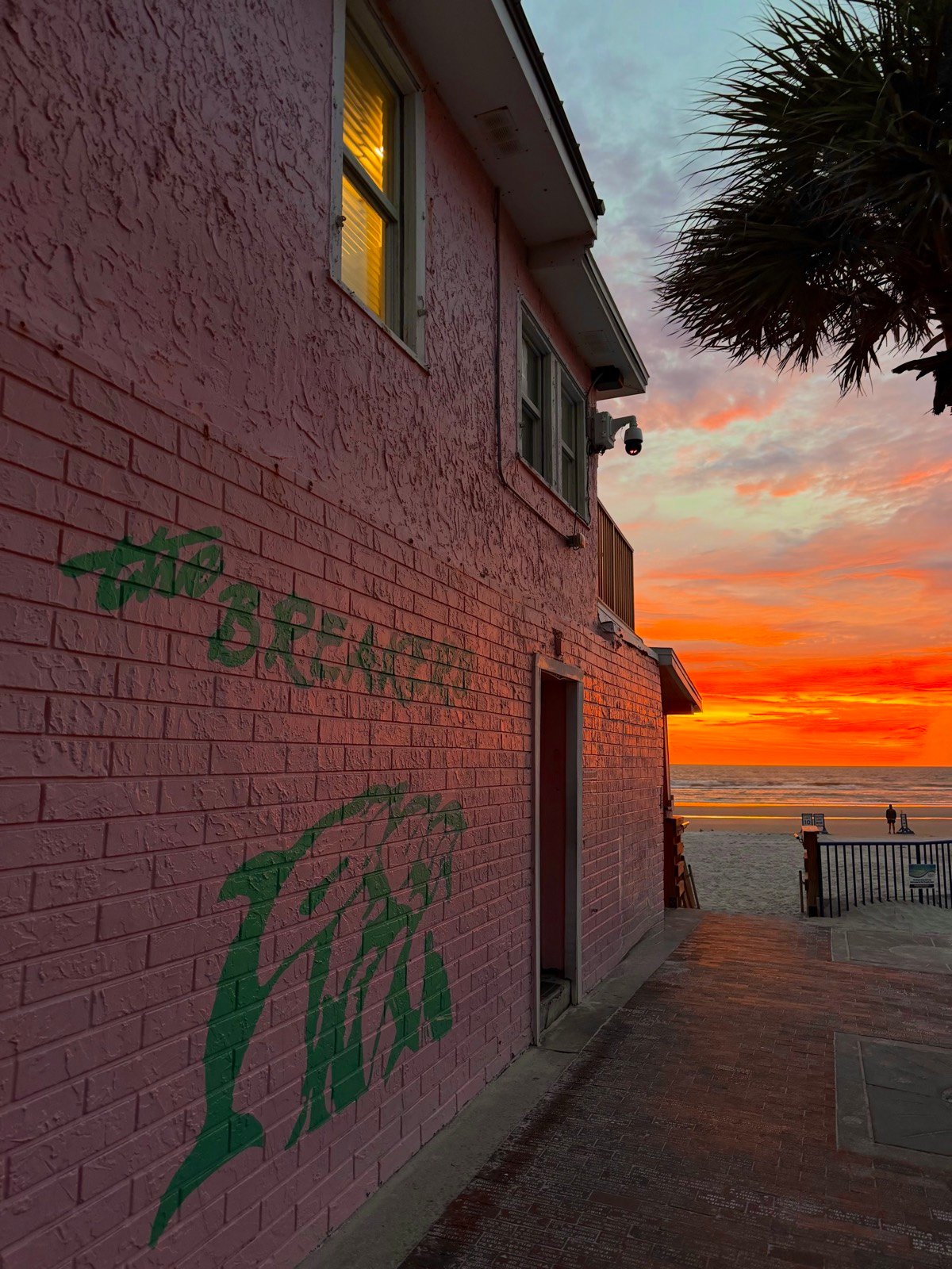 Sunrise view of the pink Breakers building and the beach from the alley beside the restaurant